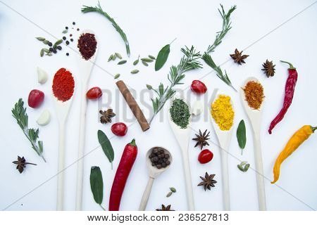 Cooking Hot Spicy Food Concept. Dry Spices And Herbs In Wooden Spoons, Fresh Herbs, Cherry Tomatoes 