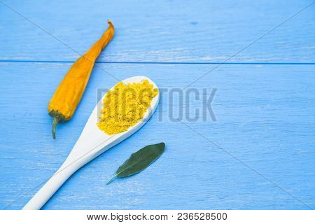 Cooking Hot Spicy Food Concept. Dry Spices In Wooden Spoon And Dry Yellow Chili Pepper On Blue Woode