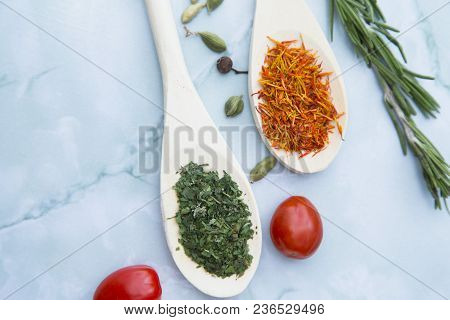 Cooking Hot Spicy Food Concept. Dry Spices And Herbs In Wooden Spoons And Cherry Tomatoes, White Mar