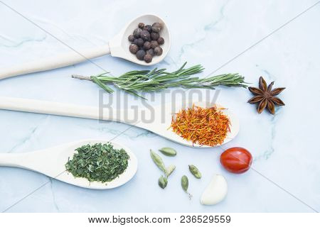 Cooking Hot Spicy Food Concept. Dry Spices And Herbs In Wooden Spoons, Fresh Herbs And Beans, White 
