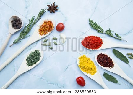 Cooking Hot Spicy Food Concept. Dry Spices And Herbs In Wooden Spoons, Fresh Herbs And Beans, White 