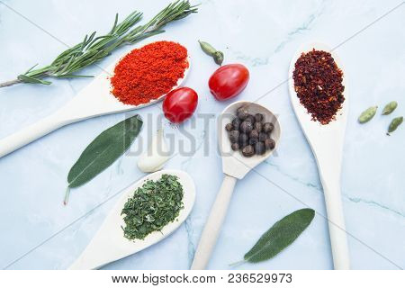 Cooking Hot Spicy Food Concept. Dry Spices And Herbs In Wooden Spoons, Fresh Herbs And Cherry Tomato