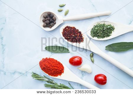 Cooking Hot Spicy Food Concept. Dry Spices And Herbs In Wooden Spoons, Fresh Herbs And Cherry Tomato