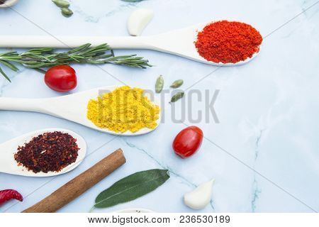 Cooking Hot Spicy Food Concept. Dry Spices And Herbs In Wooden Spoons, Cinnamon And Fresh Herbs, Whi