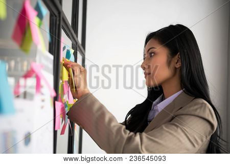 Creative Businesswoman Putting Her Ideas On Glass During A Presentation In Meeting Room. Setup Studi