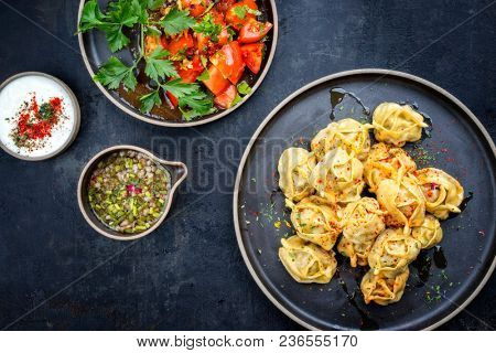 Traditional Kazakh manti steamed with mincemeat and tomato salad as top view on a modern style plate 