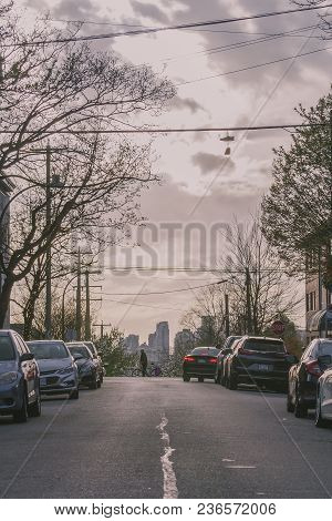 A City Cyclist Crosses The Street At Sunset On Commercial Drive In East Vancouver