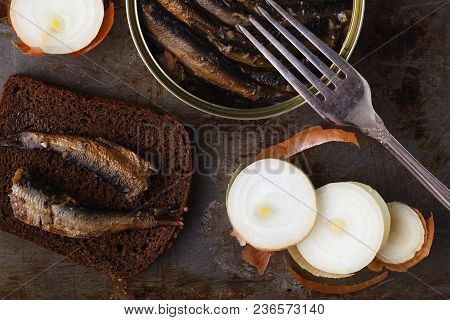 Canned Sprats In Tin Can With Rye Bread. On Rustic Background