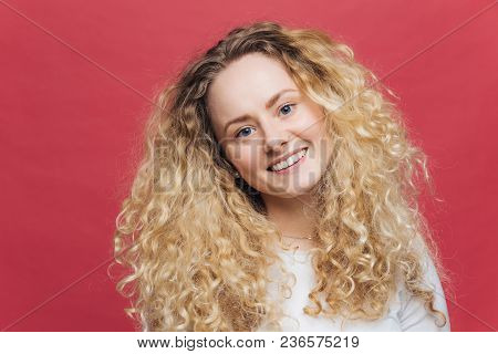 Happy Delighted Good Loking Female With Positive Expression, Curly Bushy Hair, Smiles Joyfully At Ca
