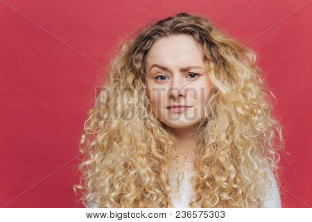 Young Attractive Woman Has Discontent Expression, Raises Eyebrow In Bewilderment, Being Dissatisfied