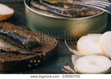 Canned Sprats In Tin Can With Rye Bread. On Rustic Background