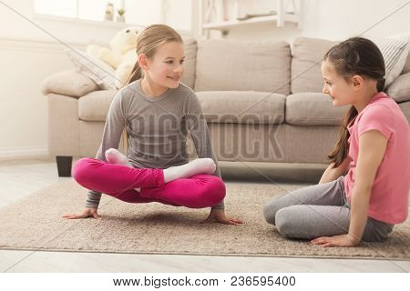 Little Girls Or Sisters Training Yoga Together Indoors, At Home. Family, Sport, Yoga, Health Concept