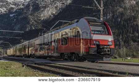Red Electric Fast Train In Austria Alps Mountains In Sunny Spring Day