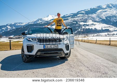 Austria, Alps - March 25, 2018: Young Man By The Latest Brand Of New White 2018 Range Rover Evoque. 