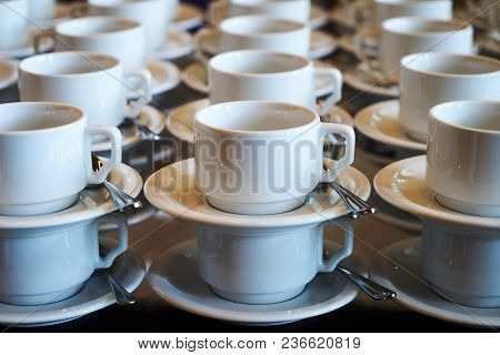 Set Of Empty White Ceramic Tea Or Coffee Cup And Saucers. Group Of Empty Cups Stacked In Rows For Se