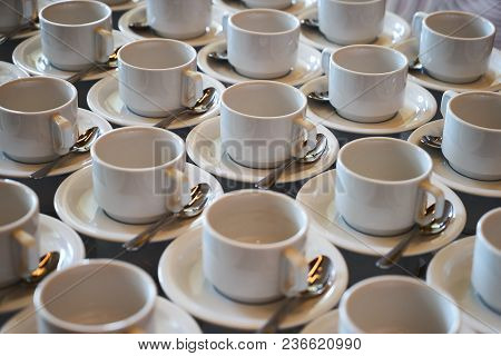 Set Of Empty White Ceramic Tea Or Coffee Cup And Saucers. Group Of Empty Cups Stacked In Rows For Se