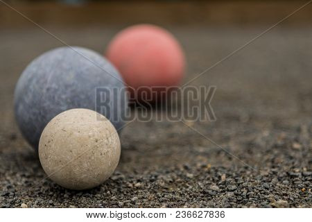 Close Up Of Three Bocce Balls With White In Focus On Gravel