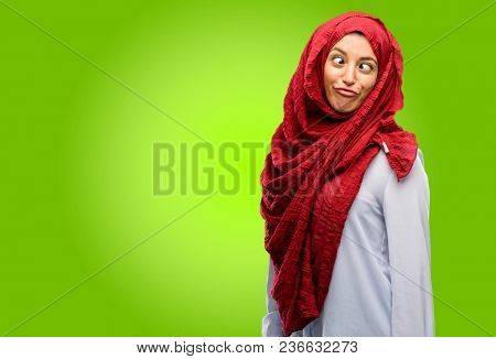 Young arab woman wearing hijab making funny face fooling