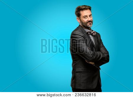 Middle age man, with beard and bow tie with crossed arms confident and happy with a big natural smile laughing