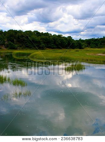 Reflections Of Fluffy Clouds On Calm, Still Water On Cape Cod Massachusetts.