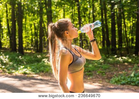 Young Woman Drinking Water After Running Outdoors.
