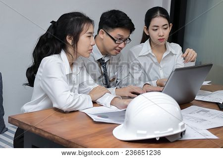 Group Of Cheerful Young Asian Business People Working Together On A Laptop Computer At Office. Teamw