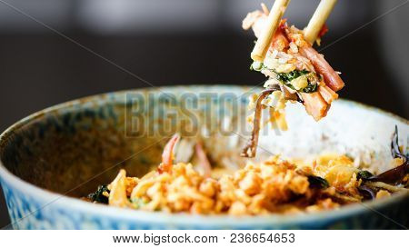 Man's Hand Holding Chopsticks Over A Plate Of Japanese, Thai, Chinese Meal - Rice, Mushroom, Vegetab