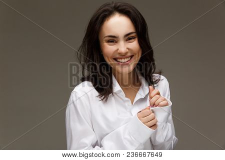 Beautiful Girl In A White Shirt Shows Emotions - Smile, Fun. On A Light Background.