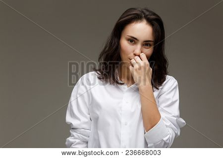 Beautiful Girl In A White Shirt Shows Emotions. On A Light Background.