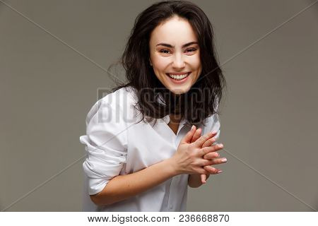 Beautiful Girl In A White Shirt Shows Emotions - Smile, Fun. On A Light Background.