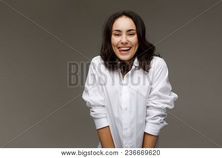 Beautiful Girl In A White Shirt Shows Emotions - Smile, Fun. On A Light Background.
