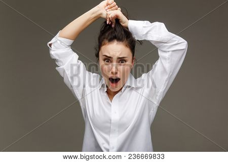 Beautiful Girl In A White Shirt Shows Emotions. On A Light Background.