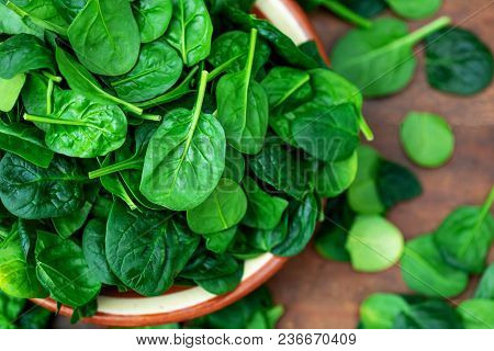 Fresh Baby Spinach Leaves In A Bowl On Rustic Wooden Background, Top View.