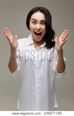 Beautiful Girl In A White Shirt Shows Emotions. On A Light Background.