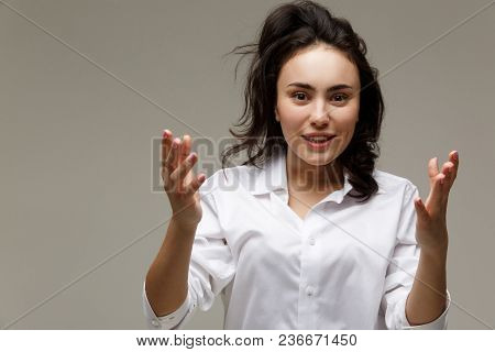 Beautiful Girl In A White Shirt Shows Emotions. On A Light Background.