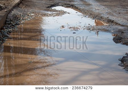 The Bad Asphalted Road With A Big Pothole Filled With Water. Dangerous Destroyed Roadbed. Mirror Ref