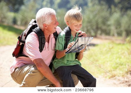 Senior homme lecture carte avec petit-fils sur balade champetre