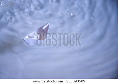 small folded paper ship on white water as symbold for transportation and tourism