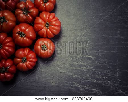 Photo Of A Table Top With Marmande Tomatoes Over A Slate Background.