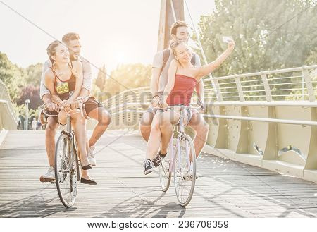 Happy Friends Taking Photo Selfie With Smartphone On Bicycle - Young Students Having Fun Together Ri