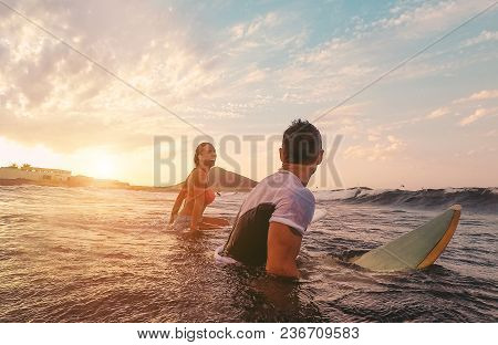Fit Couple Surfing At Sunset - Surfers Friends Having Fun Inside Ocean - Extreme Sport, Travel, Heal