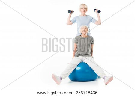 Two Senior Sportswomen With Fitness Ball And Dumbbells Isolated On White