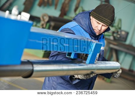 Sheet metal folding. industrial worker with piple on rolling bending machine