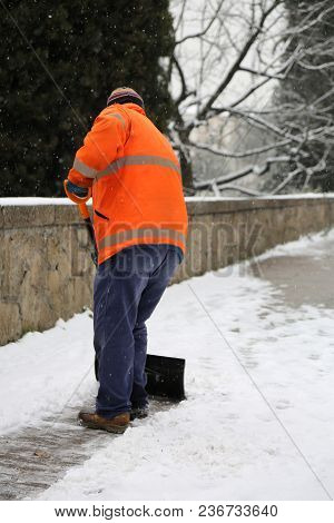 Snow Spreader With High Visibility Jacket Shovels The Sidewalks After The Snowfall In Winter