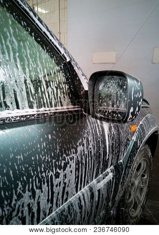 Car Wash. The Foam Flows Down And Dissolves Dirt On The Right Door And The Car Rearview Mirror.