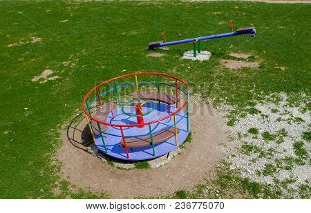 Children's Iron Carousel. Children's Playground. Swing, Carousel And Slide