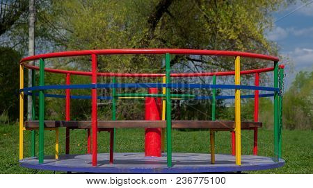 Children's Iron Carousel. Children's Playground. Swing, Carousel And Slide