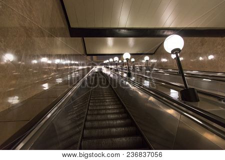 Escalator In The Subway Lifting Up With Round Lighting Lamps On The Sides