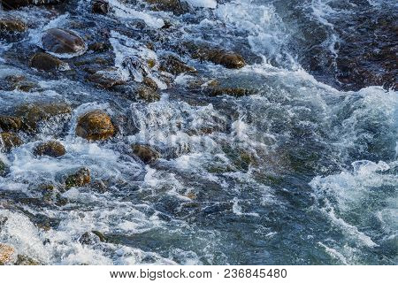 Raging Water Breaker Among Icy Rocks With Frazil Of Mountain River In Winter