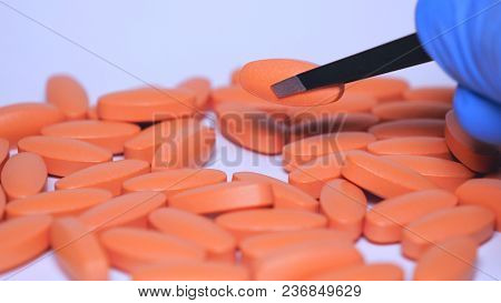 The Pharmacist Looks At Different Pills, Blue Rubber Gloves, A White Background.